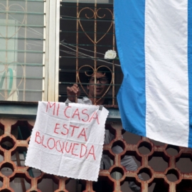 Cuban dissident and leader of Archipielago movement Yunior Garcia looks out his apartment's window showing a sign reading My house is blocked, in Havana, on November 14, 2021. - Garcia, leader of the demonstration called for November 15, denounced on Friday November 12 that Cuban State Security agents warned him that they will arrest him if he tries to march alone on Sunday, as planned. (Photo by AFP) (Photo by STR/AFP via Getty Images)